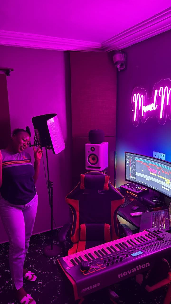 An artist performing beside the vocal booth, with the desk and keyboard behind