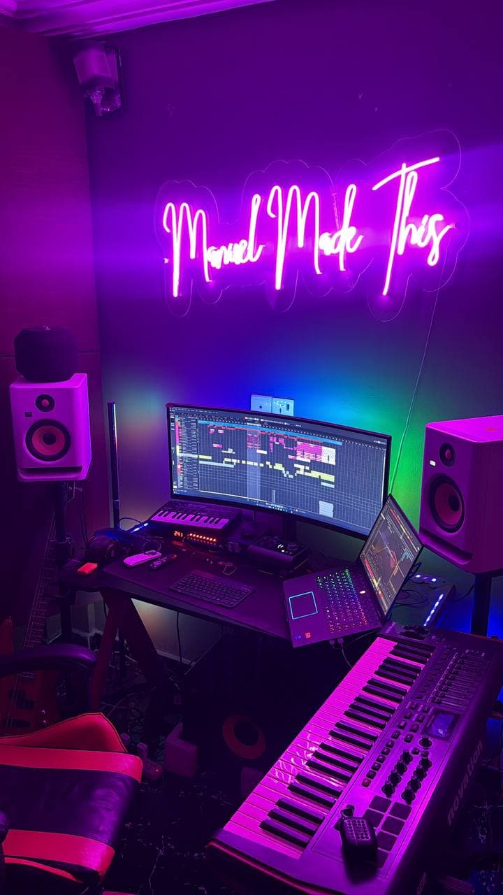 The full desk setup under the ManuelMadeThis neon sign