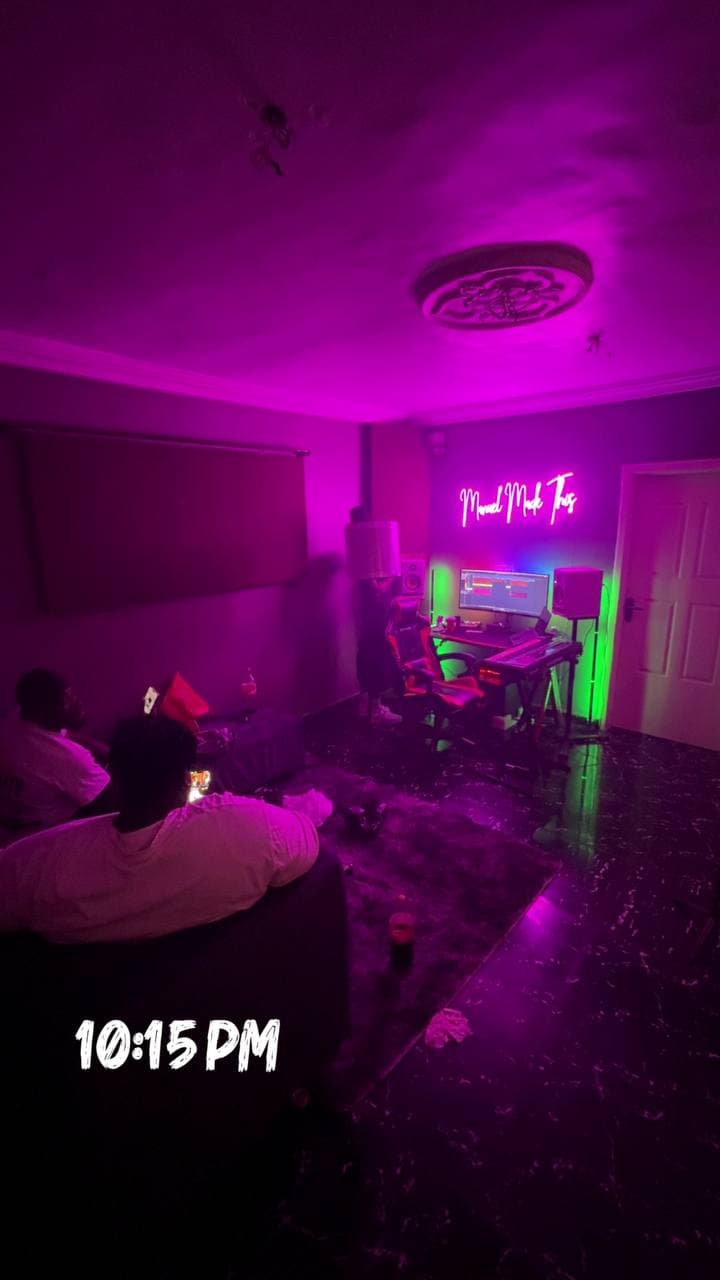 People on the sofa late at night, the desk glowing under the neon sign, with “10:15 PM” written across the photo