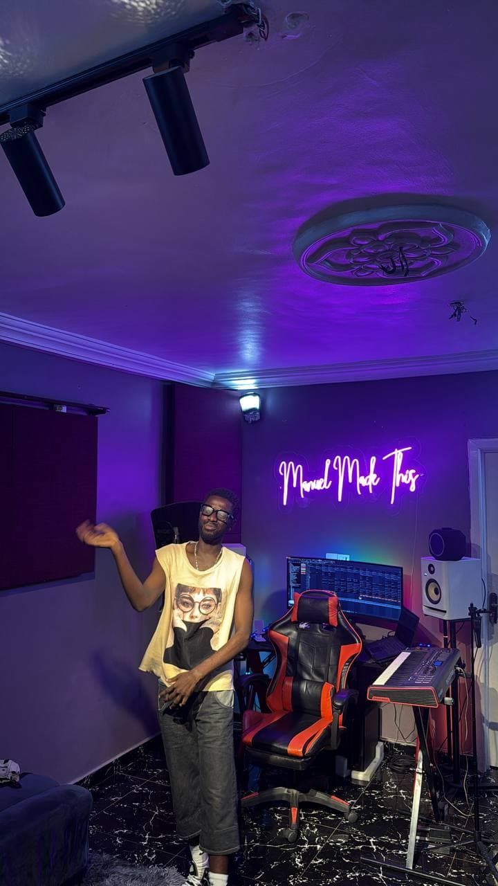 An artist posing in front of the desk and neon sign